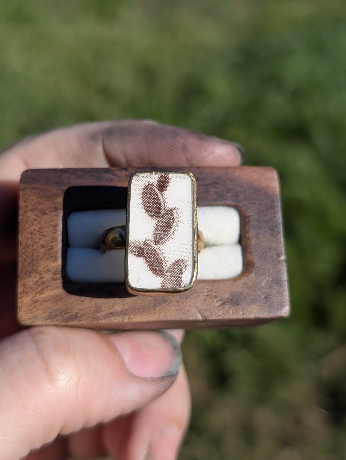 Rectangular reclaimed china ring with a brown cactus design, displayed in a wooden ring box.