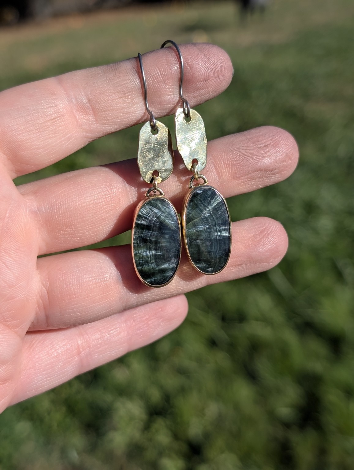 Green oval seraphinite earrings below hammered metal links and niobium hooks.